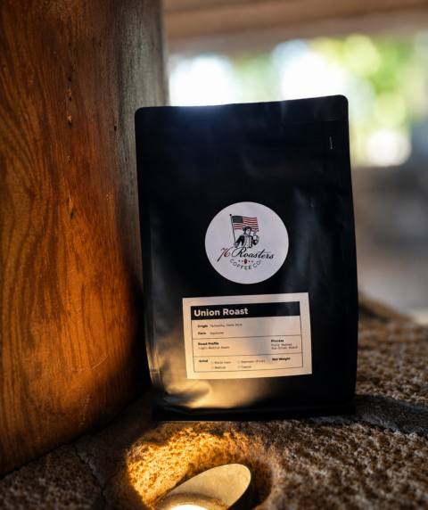 Black coffee bag labeled Union Roast from 76 Roasters Coffee Co., leaning against a wooden post with a circular logo on the front cover image.